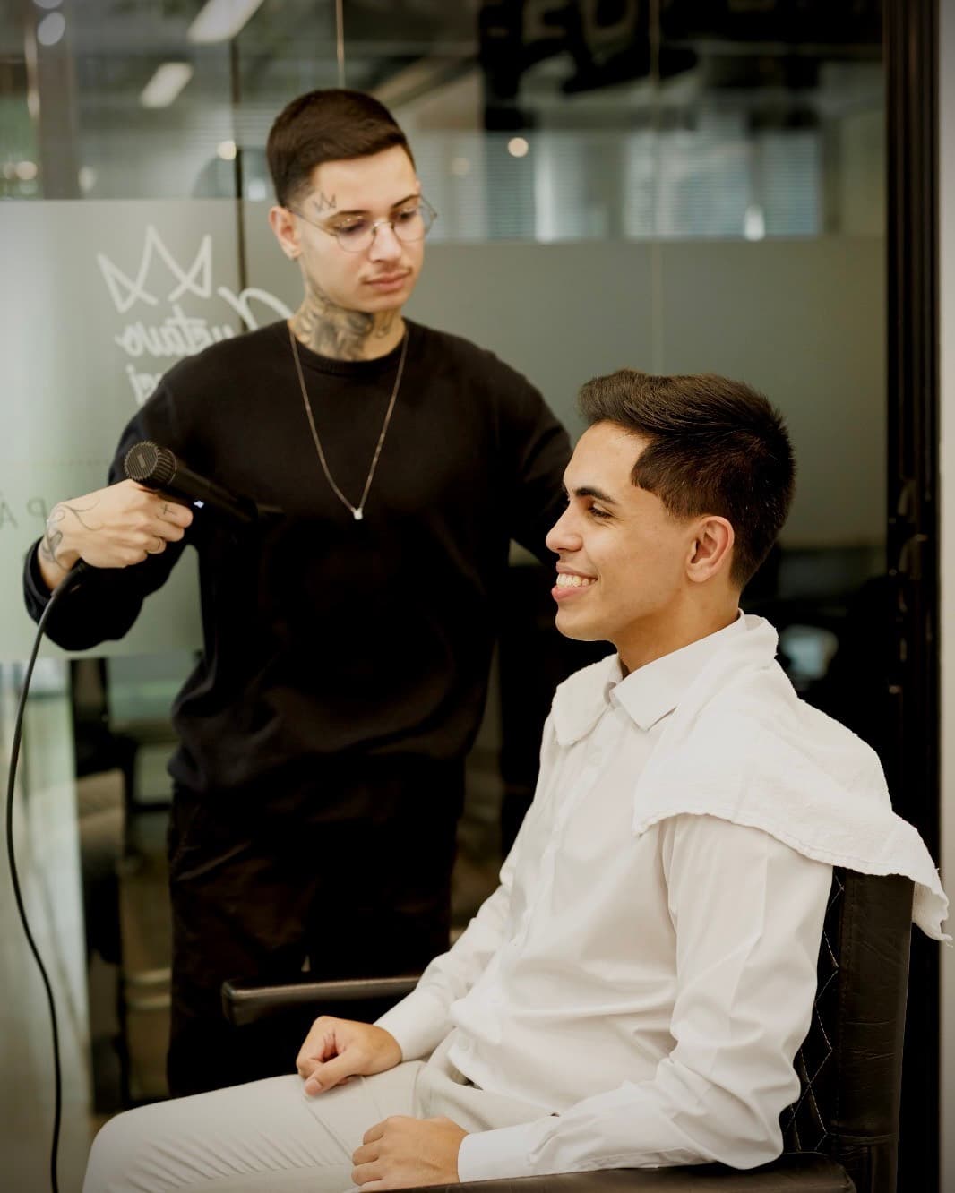 Gustavo Derussi finalizando o cabelo de um cliente com secador