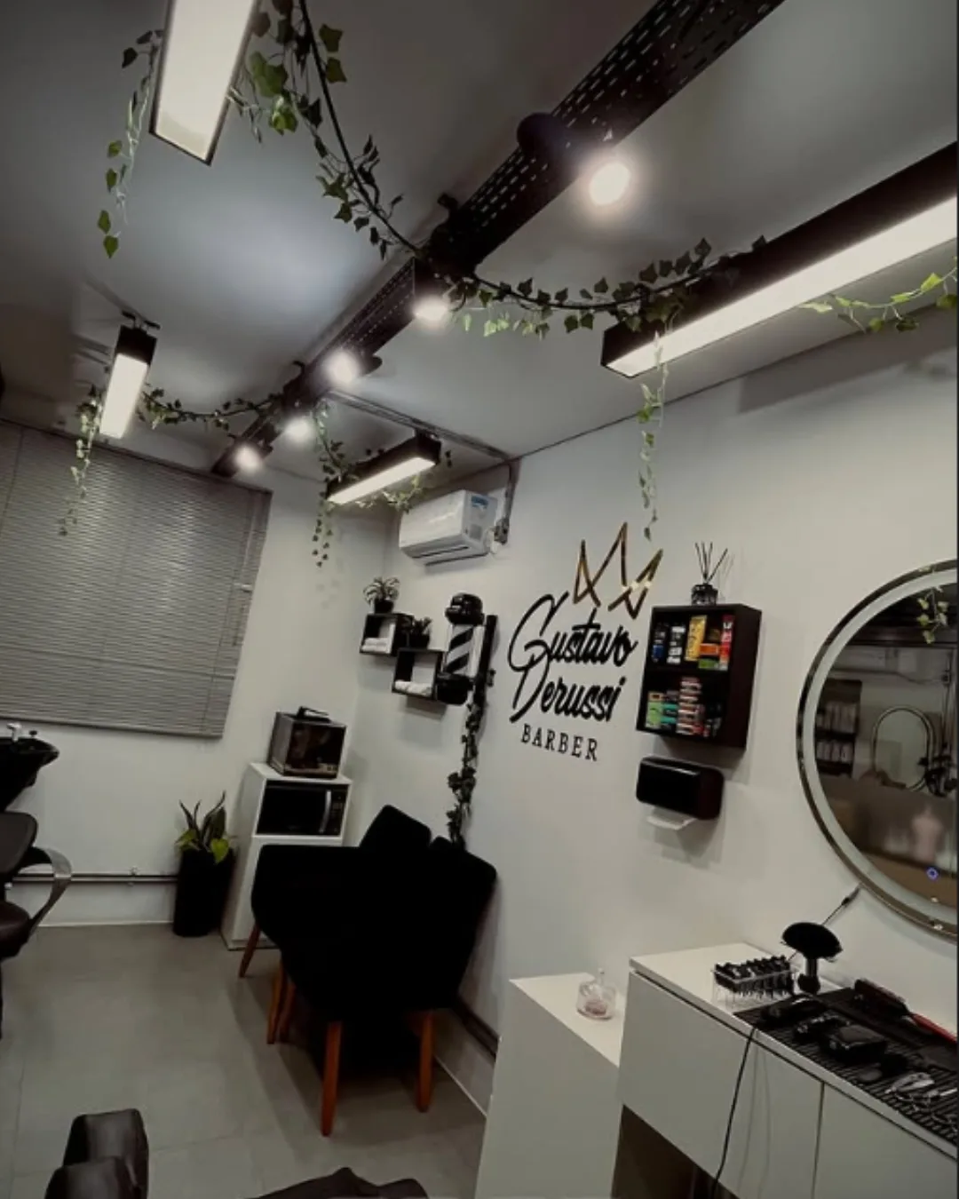 Salão da barbearia de Gustavo Derussi, com a logo na parede, no bairro América, em Joinville