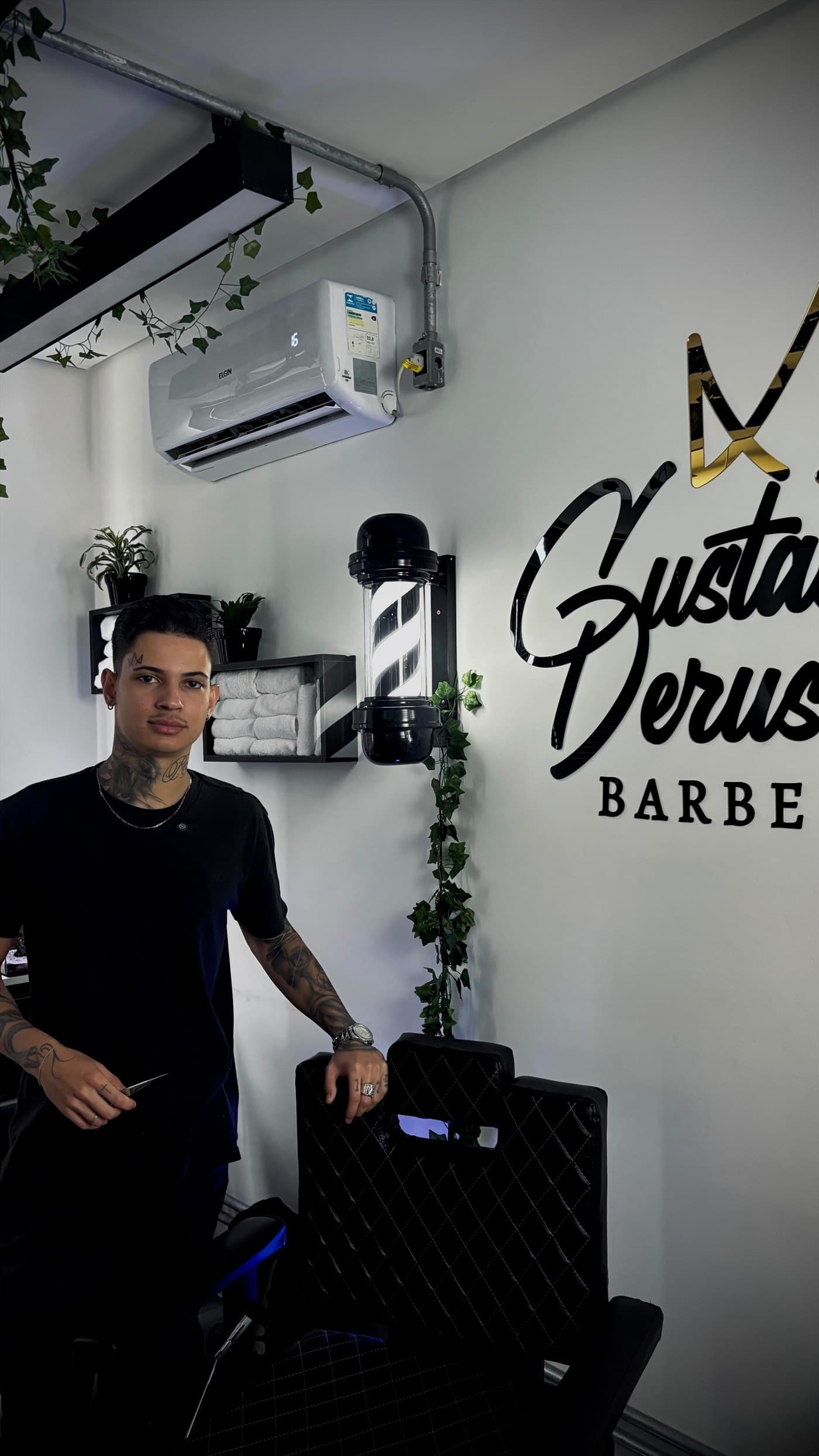 Gustavo Derussi na barbearia, ao lado da cadeira de atendimento